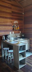 a kitchen with a counter with stools in it at Morada do Xaxim - Chalé Hortência in São Francisco de Paula