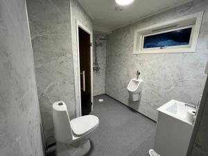 a bathroom with a toilet and a sink and a urinal at Frittliggende hytte i flott turterreng in Molde