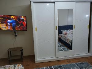 Armario blanco con espejo junto a la cama en Mena Apartment, en El Cairo