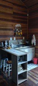 a kitchen with a sink and a counter with stools at Morada do Xaxim - Chalé Hortência in São Francisco de Paula