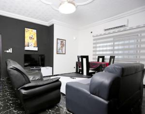 uma sala de estar com cadeiras pretas e uma televisão em Villa Flo Residence em Lomé