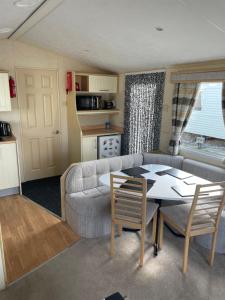 a living room with a couch and a table with chairs at Ingoldmells, Coral beach, 8 birth in Ingoldmells +12 photos
