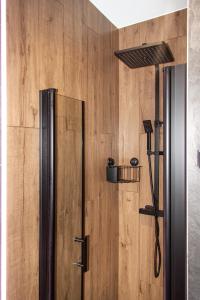 a shower in a room with a wooden wall at Brama Sanu - Bieszczady in Olchowiec