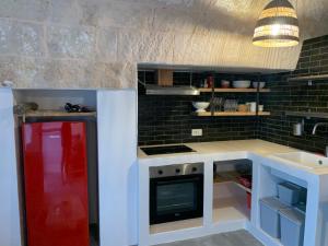 - une cuisine avec un réfrigérateur rouge à côté d'un évier dans l'établissement La Piccola Tufaia, à Fasano
