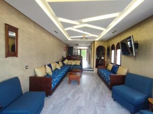 a living room with blue couches and a tv at Beach House in KSAR RIMAL in Marina Smir