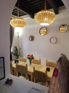 a dining room with a table and chairs and chandeliers at Charmant riad pour familles ou groupes - Dar Mama in Essaouira