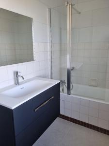 La salle de bains est pourvue d'un lavabo, d'une baignoire et d'un miroir. dans l'établissement Chambre dans maison à partager, à Talensac