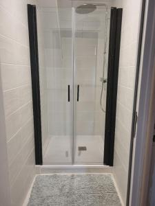 La salle de bains est pourvue d'une douche avec une porte en verre. dans l'établissement Chambre dans maison à partager, à Talensac