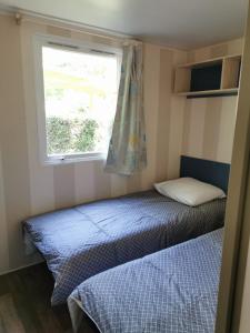 a small bedroom with two beds and a window at Mobile Home ~ Parc des Roches in Saint-Chéron