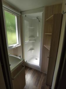 a small bathroom with a shower and a sink at Mobile Home ~ Parc des Roches in Saint-Chéron