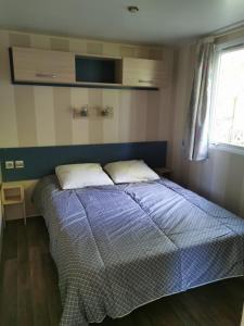 um quarto com uma cama com um edredão azul e uma janela em Mobile Home ~ Parc des Roches em Saint-Chéron