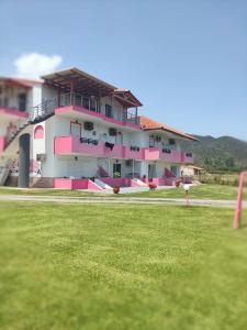a pink and white building with a grass field at Vigla House in Sykia Chalkidikis