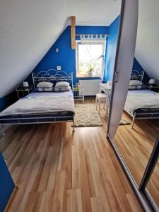 a bedroom with two beds and a blue wall at Widok na Śnieżkę in Miłków