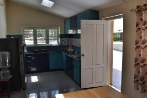 a kitchen with blue cabinets and a white door at Rochas Valley Homestay in Suntikoppa