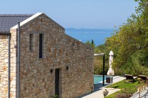 a stone house with a swimming pool and a patio at Elaionas Estate Perdika in Perdika