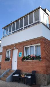 un edificio con dos sillas y una mesa frente a él en VIVIENDA VACACIONAL "EL CANXILÓN" Situada en Lastres - Zona Oriente de ASTURIAS - Casa independiente - Terraza con vistas al mar a 800 m de la playa, en Lastres