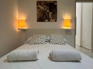 a bedroom with a bed with two pillows and two lights at Bungalow 97 in Fontane Bianche