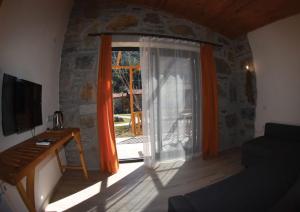 una sala de estar con una gran ventana con cortinas de color naranja en Begonvillage Tatil Evleri, en Datça