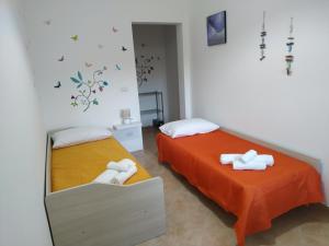 2 Betten in einem Zimmer mit orangefarbener Bettwäsche in der Unterkunft "Babbo" Nicola in Salve