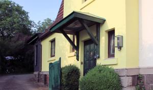 uma casa amarela com uma porta verde em Charmante Wohnung am Schönberg em Sonneberg