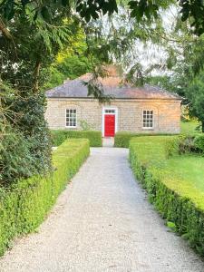 ein Backsteinhaus mit einer roten Tür und einer Auffahrt in der Unterkunft The Nurseries in Boyle