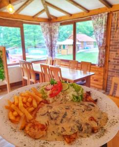 um prato de comida numa mesa com batatas fritas em Etno selo BISTROVO em Vitez