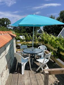 una mesa y sillas con una sombrilla azul en una terraza en Saumur, proche, les 3 gîtes, en Saint-Martin-de-la-Place