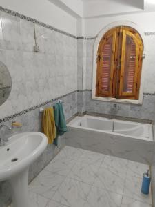 Baño blanco con bañera y lavamanos en Gabawy Garden Ferienwohnung en Luxor
