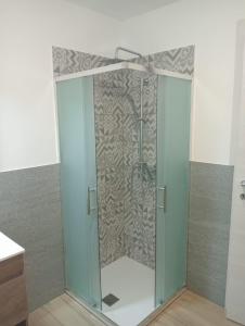 a glass shower door in a bathroom with a wall at Maison Loren Pila in Cerise