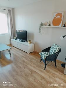 a living room with a tv and a chair at Spacieux appartement en duplex in Merlimont