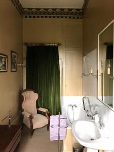 uma casa de banho com uma cortina verde, uma cadeira e um lavatório. em Chateau de Vesset em Tréteau