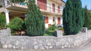 un muro di pietra con alberi di fronte a un edificio di Apartman Roža a Matulji (Mattuglie)