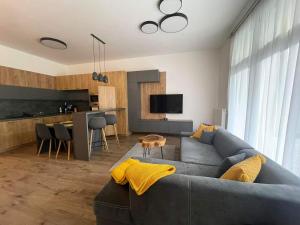 a living room with a gray couch and a kitchen at Apartmán TATRAFUN in Tatranská Lomnica