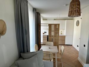 a living room with a table and chairs and a kitchen at Nida, Vėtrungių 7 apartamentai prie marių in Nida