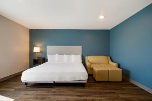 ein Schlafzimmer mit einem Bett und einem gelben Stuhl in der Unterkunft WoodSpring Suites Panama City Beach in Panama City Beach