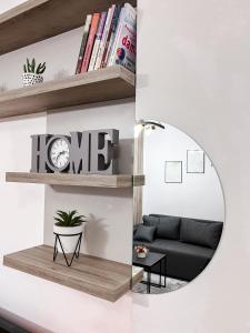 een woonkamer met een ronde spiegel en een zwarte bank bij Apartman Vas dom 2 in Kraljevo