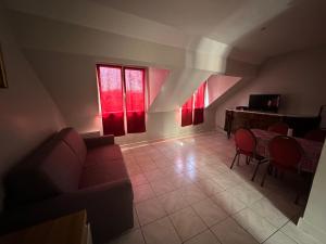 ein Wohnzimmer mit einem Sofa, einem Tisch und roten Fenstern in der Unterkunft appartement meublé in Vincennes