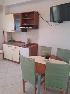 a kitchen with a table and chairs and a television at Apartmani ante 3 in Drašnice