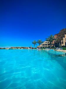 ein großer Pool mit blauem Wasser mit Gebäuden und Palmen in der Unterkunft Telal Al Sukhna Only families in Ain Suchna