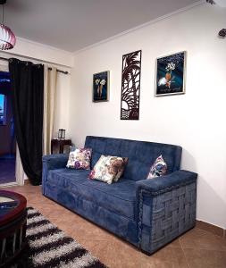 艾因蘇赫納的住宿－Telal Al Sukhna Only families，客厅里一张蓝色的沙发,墙上挂着照片