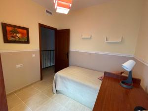 a bedroom with a bed and a desk with a lamp at Esencias Azahar in Chiclana de la Frontera