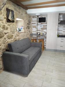 sala de estar con sofá y pared de piedra en A CASIÑA DA PALMERA, en Vilar