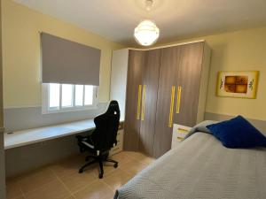 um quarto com uma secretária, uma cama e uma cadeira em Esencias Azahar em Chiclana de la Frontera