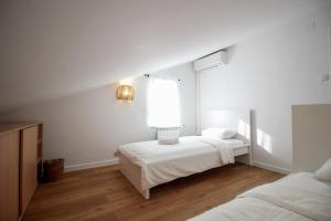 a white bedroom with two beds and a window at Apartment Castelmuschio in Omišalj