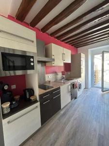 a large kitchen with white appliances and red walls at Appartement plein de charme in Coignières