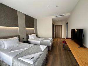 a hotel room with two beds and a flat screen tv at Frojd Kune Resort & Beach Hotel in Shëngjin