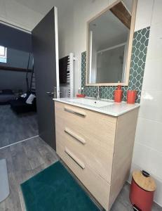 a bathroom with a sink and a mirror at Appartement plein de charme in Coignières