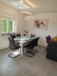 a dining room with a white table and black chairs at Lunisa VS1 Apartment in Kostrena