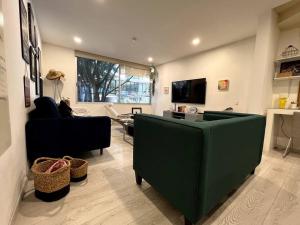 ein Wohnzimmer mit einem grünen Sofa und einem TV in der Unterkunft Stunning duplex in the best area of Roma Norte in Mexiko-Stadt