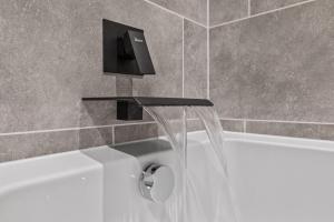 a bath tub with a faucet and a sink at The Riverside Rest in Stirling